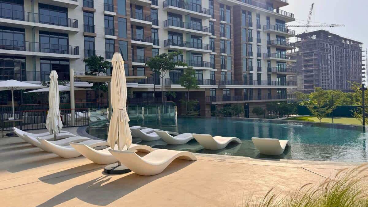 Et moderne hotel med swimmingpool, liggestole og udsigt til de omkringliggende bygninger.