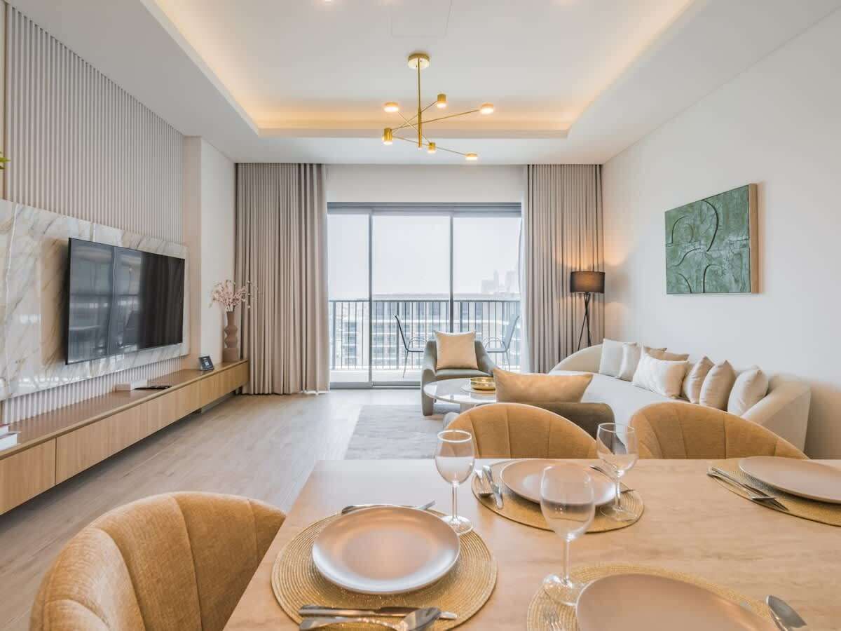 A modern living room with a dining area, a television, and a balcony with a view.