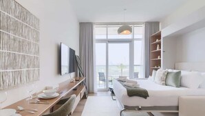 Camera d'albergo moderna con un letto, una scrivania con sedia, una televisione e un'ampia finestra con vista.