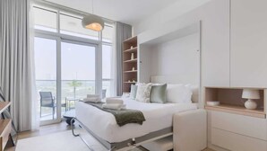 Camera d'albergo moderna con un letto grande, un comodino, una sedia, una scrivania e vista all'esterno.