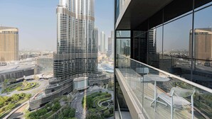 A high-rise building with a modern glass facade, surrounded by other high-rise buildings and a landscaped area with pathways and greenery. - Full Burj Khalifa View, Premium 3BR Furnished Unit (Dubai)