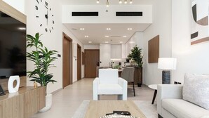 Ein modernes Wohnzimmer mit Sofa, Couchtisch und Fernseher. Eine Pflanze und eine Lampe stehen daneben.