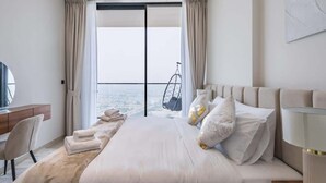 Un hotel moderno con una cama grande, un escritorio y vistas al mar.
