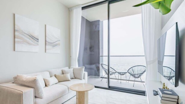 Una sala moderna con sofá, una mesa de centro y un balcón con sillas.
