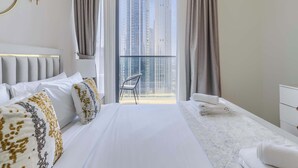 Een moderne hotelkamer met een groot bed, een balkon met een stoel en uitzicht op hoge gebouwen.