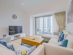 A modern living room with a flat-screen TV, a wooden coffee table, and two sofas with patterned cushions. - Sleek 2BR High-Rise Stay in Vibrant Dubai Marina (Dubai)