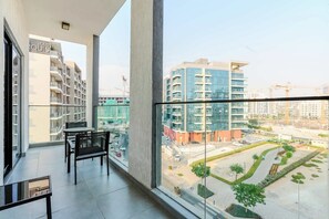 Ein Balkon mit Blick auf einen modernen Gebäudekomplex, einem Glastisch und Stühlen.