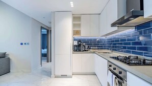 A modern kitchen with white cabinets, a blue-tiled backsplash, a built-in oven, and a gas stove. - Pool View, Fully Furnished, Prime Location! (Dubai)