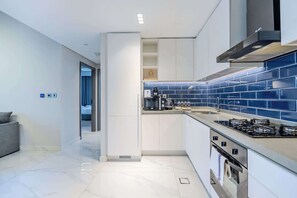 A modern kitchen with white cabinets, a blue-tiled backsplash, a built-in oven, and a gas stove. - Pool View, Fully Furnished, Prime Location! (Dubai)