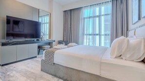 A modern hotel room with a large bed, a flat-screen TV, a desk, and a large window with curtains. - Pool View, Fully Furnished, Prime Location! (Dubai)