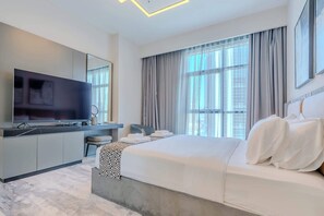 A modern hotel room with a large bed, a flat-screen TV, a desk, and a large window with curtains. - Pool View, Fully Furnished, Prime Location! (Dubai)
