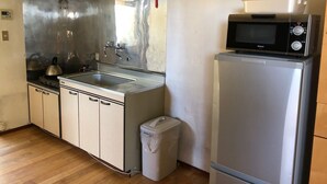 Una cocina compacta con un lavamanos de acero inoxidable, una tetera, un microondas y un refrigerador.