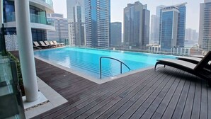 Ein Pool auf dem Dach mit Liegestühlen und Blick auf die Stadt.