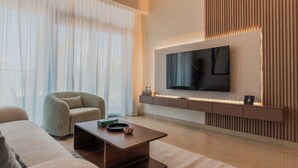 Ein modernes Wohnzimmer mit Flachbildfernseher an der Wand, einem bequemen Sessel, einem Couchtisch und einer Couch.