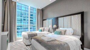 Une chambre d’hôtel moderne avec deux lits, une grande fenêtre avec des rideaux et une vue sur le paysage urbain.