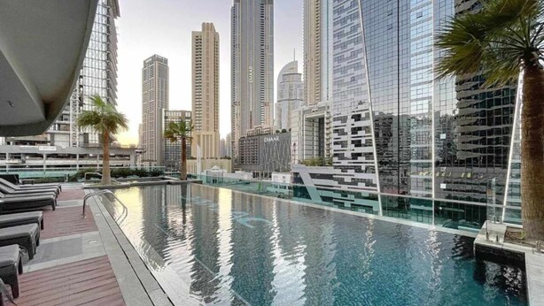 Une piscine moderne d’hôtel avec la silhouette de la ville en arrière-plan.