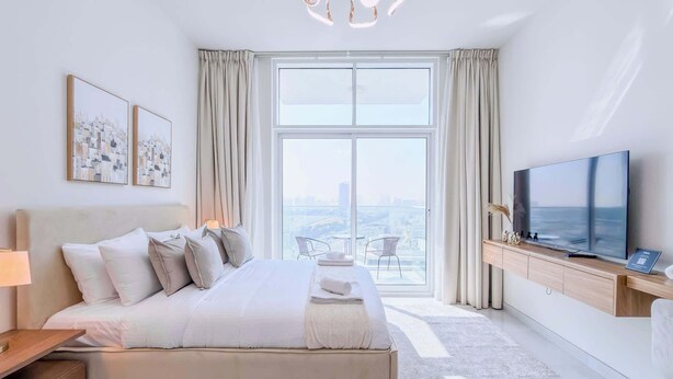 Een moderne hotelkamer met een groot bed, een televisie en uitzicht op de stad.