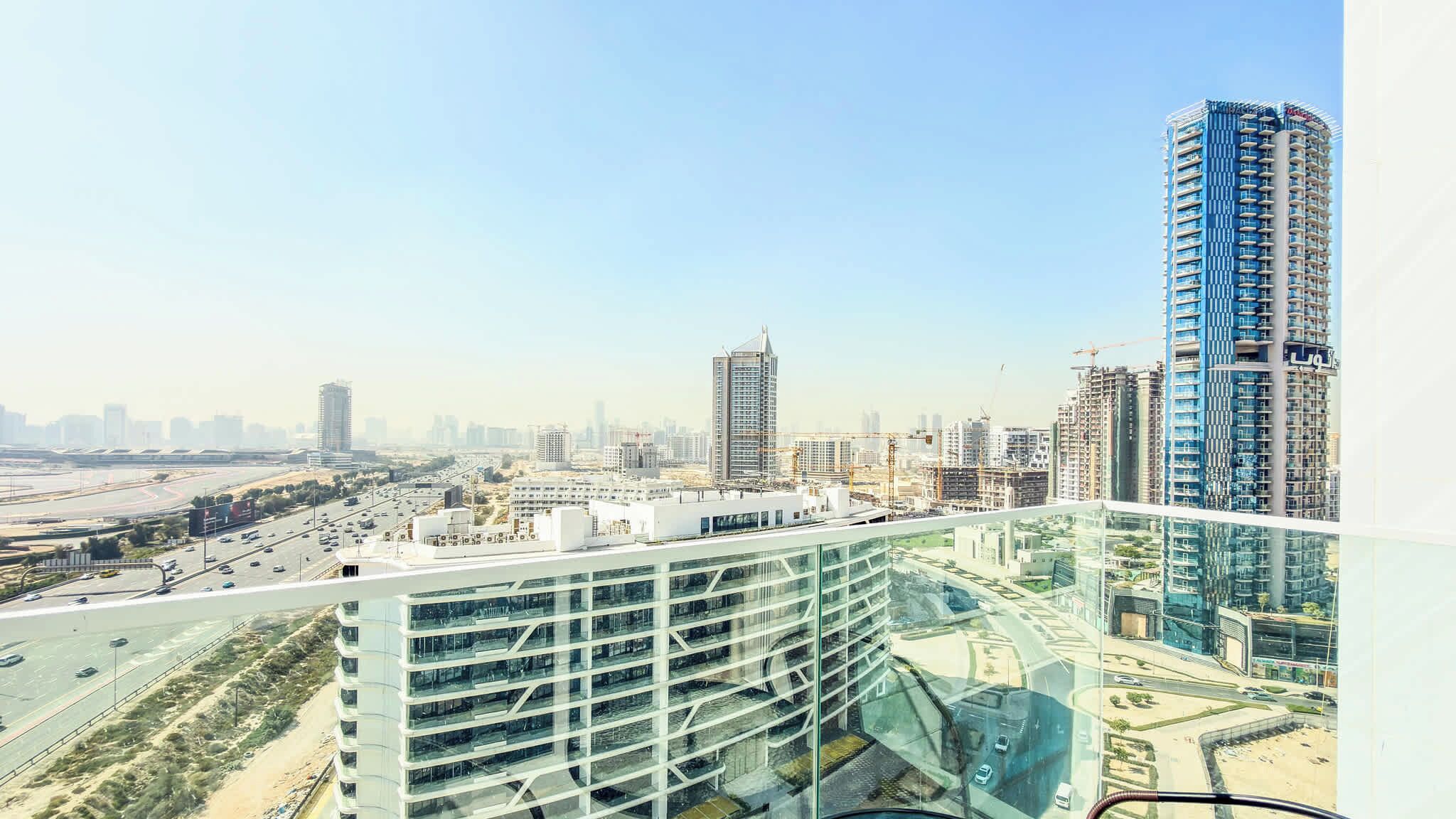 A high-rise building with a modern glass facade, surrounded by other high-rise buildings and a highway.