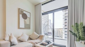 Una sala de estar moderna con un sofá, una mesita de centro, una silla colgante y un ventanal con vistas a la ciudad.