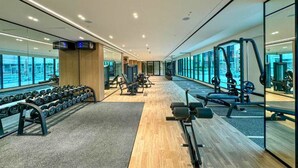 Un gimnasio moderno con paredes de espejo, equipo de levantamiento de pesas y máquinas de cardio.