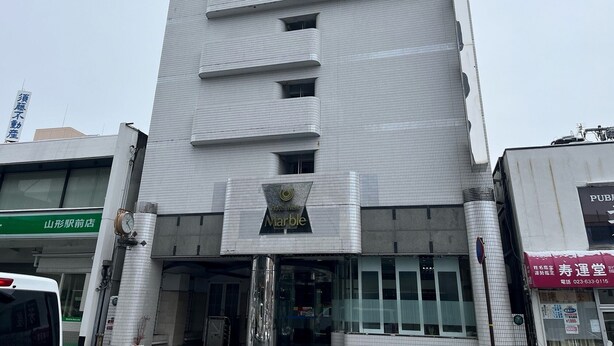 A tall, modern building with a tiled facade and a prominent hotel sign at the bottom. - Hotel New Marble (Yamagata)