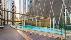Une piscine sur le toit, au design moderne, entourée d’immeubles de grande hauteur.