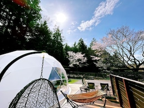 A transparent dome structure, outdoor seating, and cherry blossom trees. - Workation Resort THE Forest (Tsuru)