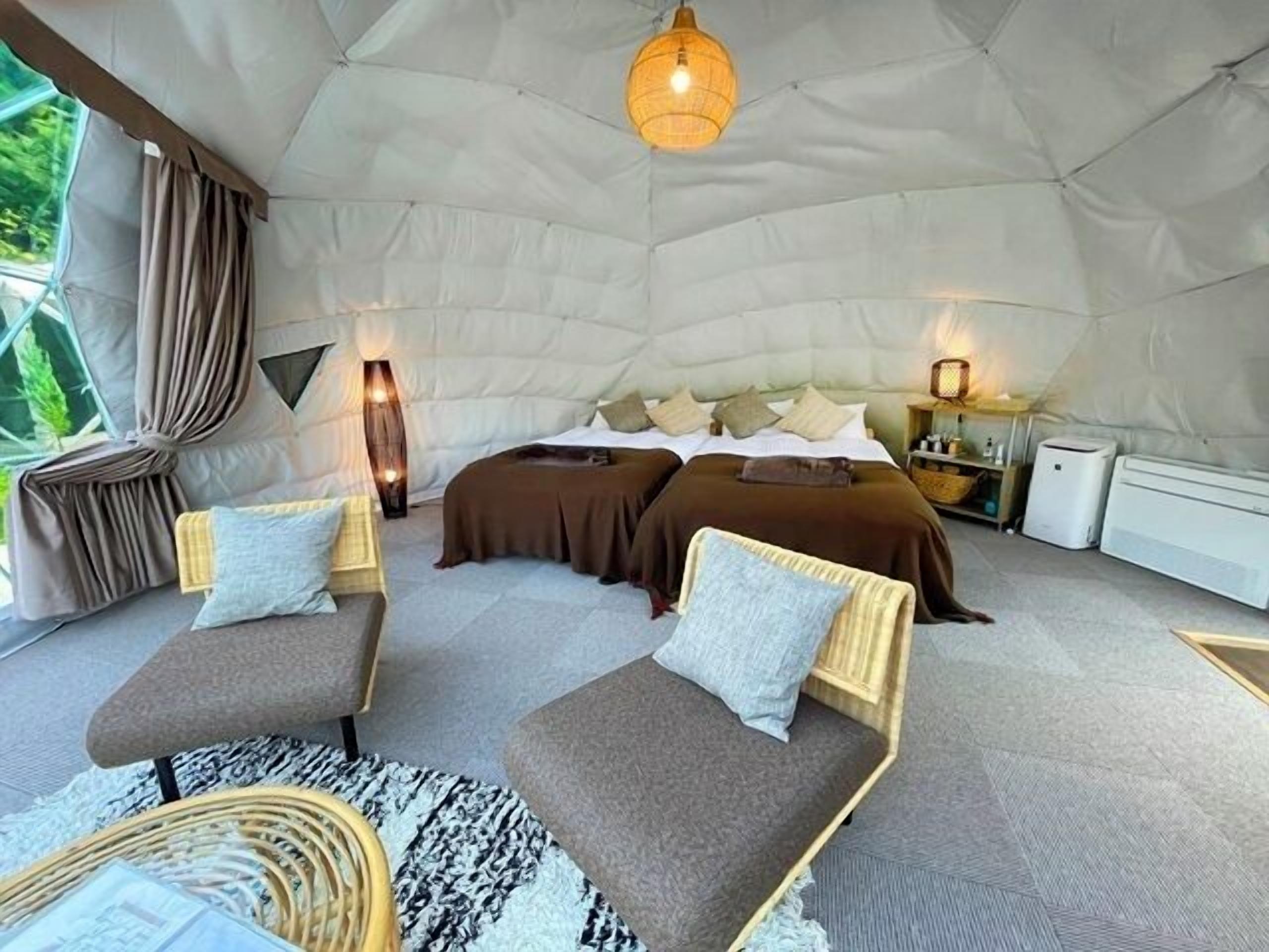 A tent-style room with two beds, a sitting area, and a small table.