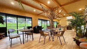 Una habitació àmplia amb terres de fusta, grans finestres i una escultura d'un arbre al centre.