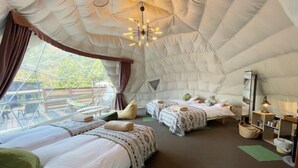 Habitació tipi acollidora i ben il·luminada amb dos llits, una làmpada penjant i vista a l'exterior.