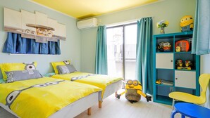 Habitación con dos camas, un escritorio, una silla y decoración temática de Minions.