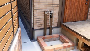 Un área de ducha con un banco de madera, una pared de ladrillo y una puerta de madera.