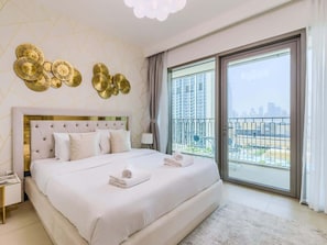 A modern bedroom with a large bed, a view of a cityscape through a balcony, and decorative wall art. - Scenic Burj Khalifa View, Downtown Location (Dubai)