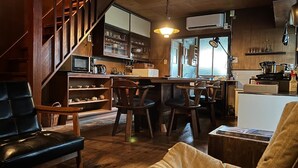 Un intérieur chaleureux avec un escalier, des meubles en bois, un coin cuisine et un espace repas.