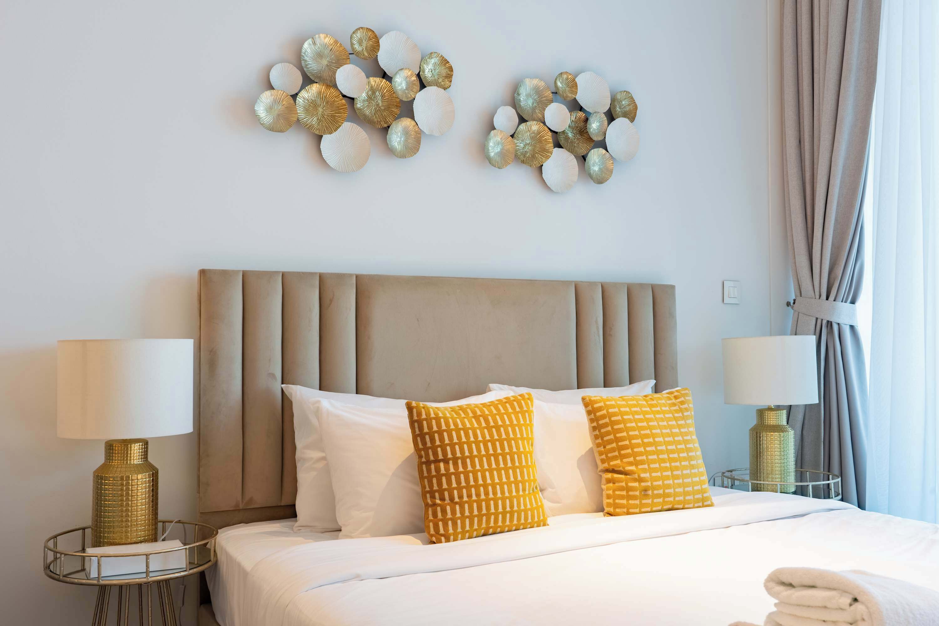 Ett hotellrum med en stor säng, två sänglampor, en sänggavel och dekorativ väggkonst.