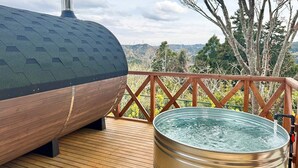 A hot tub on a wooden deck with a view of trees and hills. - Green Hotel Ibusuki (Misato)