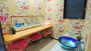 A bathroom with a vanity, a large mirror, a blue sink, and floral wallpaper. - Azama Ocean View Terrace (Hitoyoshi)