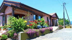 A brick house with a tiled roof, a porch, and a gravel driveway.