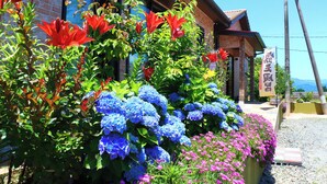 A building with a brick facade, a sign with Japanese characters, and a variety of colorful flowers in front.