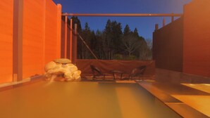 An outdoor seating area with a rock formation, chairs, and a table.