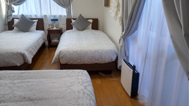 Et hotelværelse med to senge, et natbord med lampe, en radiator og et vindue med gardiner.