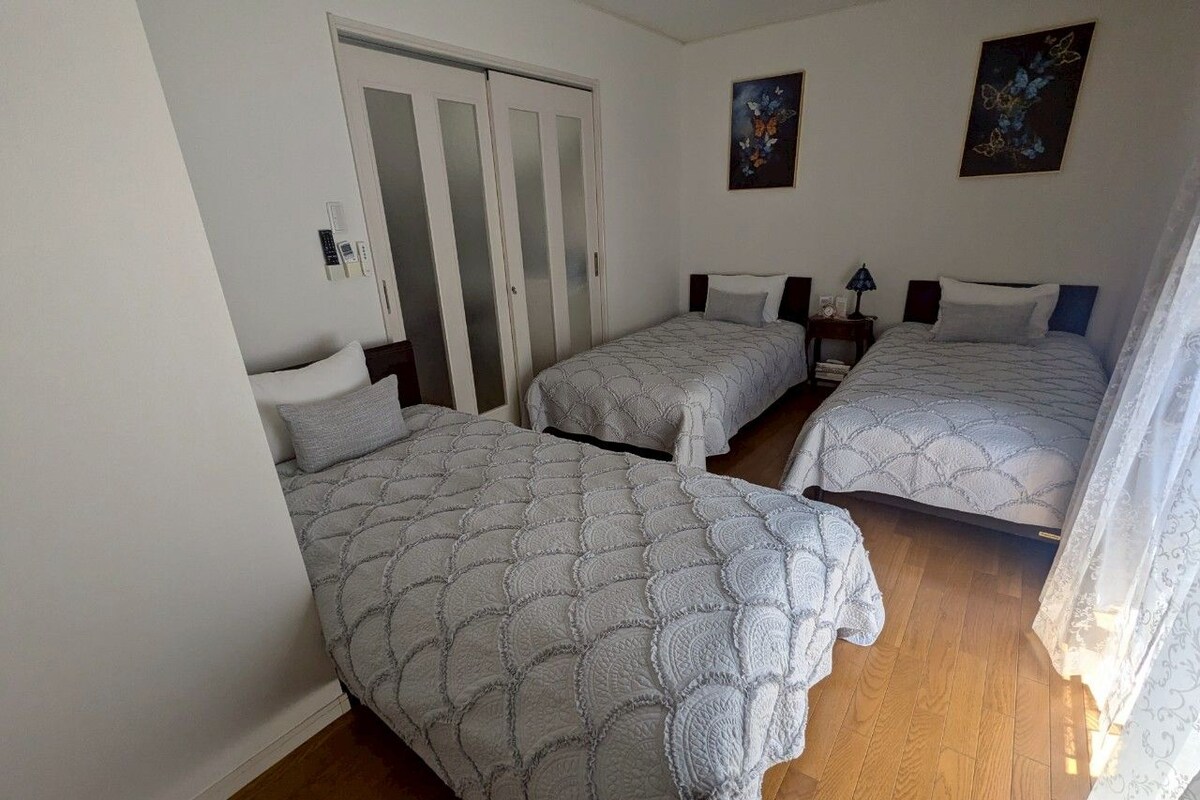 Una habitación con tres camas, un armario y una mesita de noche con lámpara.