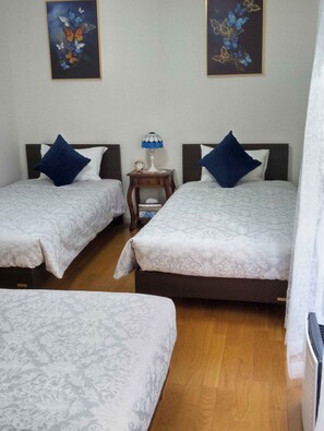 A hotel room with two beds, each with a pillow and a nightstand with a lamp. - Kitsukan (Uken)