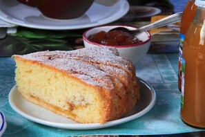 A slice of cake on a plate with a bowl of jam and a jar of jam in the background. - Le Torrette Etrusche 5 Room – Comfort and Relaxation in Capalbio (Capalbio)
