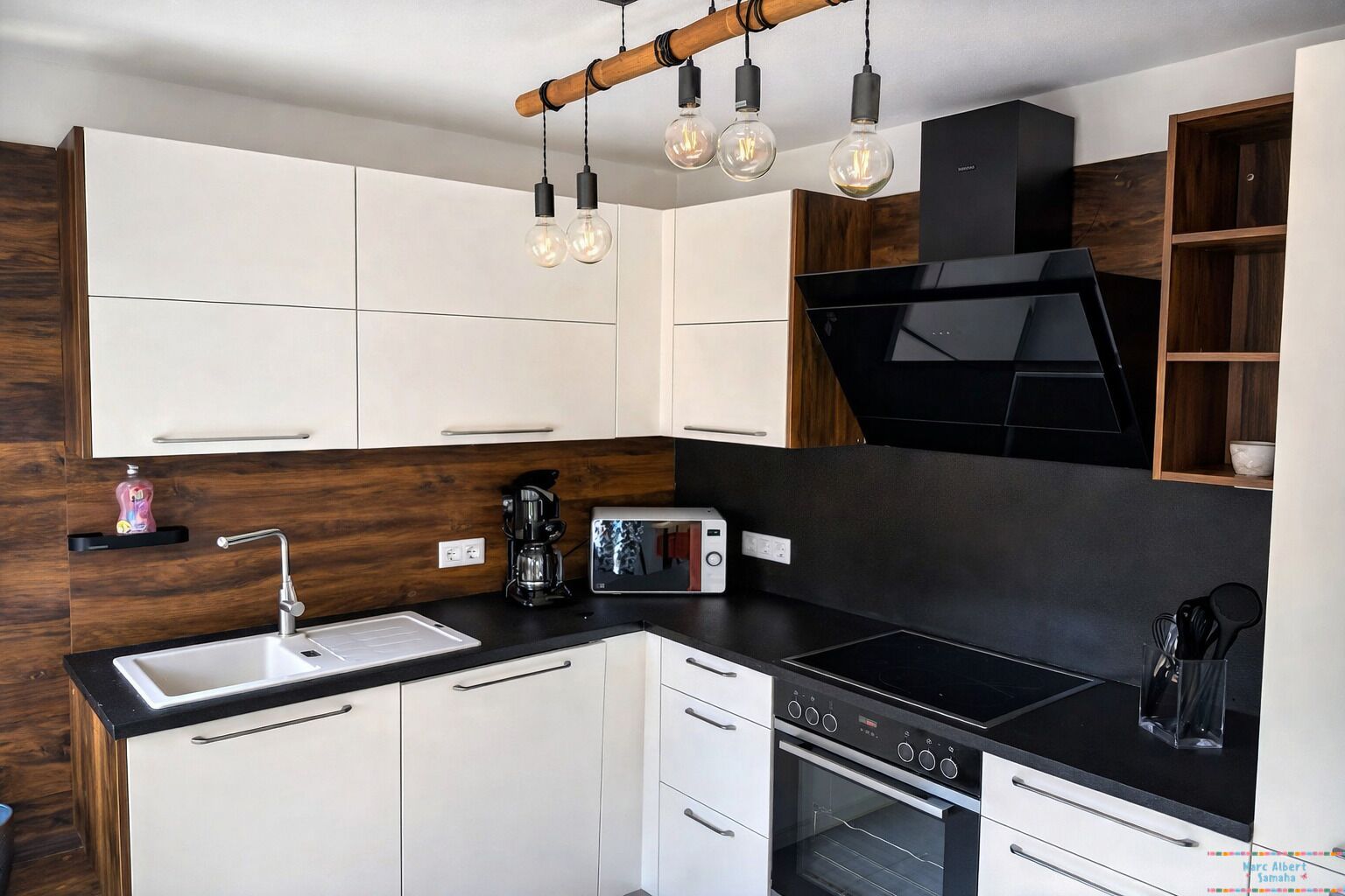 A modern kitchen with white cabinets, a black countertop, a built-in oven, a coffee maker, and a toaster.