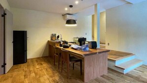 Cocina compacta con encimera de madera, un refrigerador y una zona de comedor con sillas.