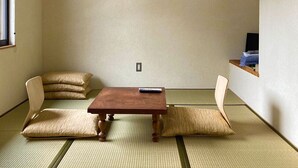 Una habitación japonesa tradicional con suelo de tatami, una mesa de madera baja y dos esterillas de tatami con cojines.