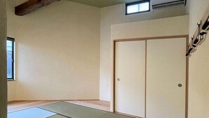 Una habitación con esteras de tatami, una puerta corredera y un ventanal pequeño.