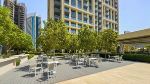 A rooftop terrace with outdoor seating and a view of high-rise buildings. - Full Burj Khalifa View, Luxury Furnished-Downtown (Dubai)