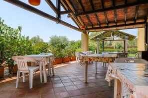 Eine Terrasse im Freien mit überdachter Sitzgelegenheit, Pflanzkübeln und einer Pergola.